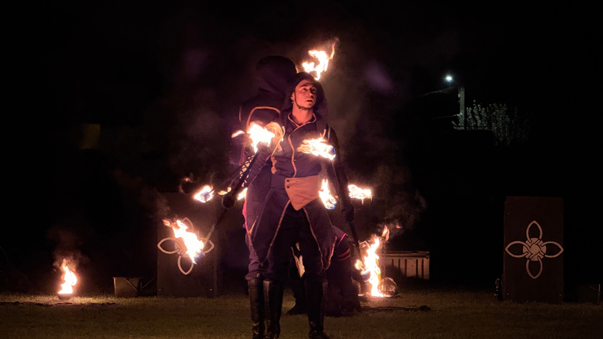sur le stade de gujan, la nuit; 2 personnes qui font un spectacle pyrotechnique en tenant des torches enflammées pour le carnaval 2026