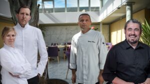 4 chefs cuisiniers : 3 hommes et une femme dans une salle de restaurant