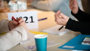 Image illustration, deux personnes à un bureau en entretien, on ne voit que leurs mains, des gobelets et des feuilles
