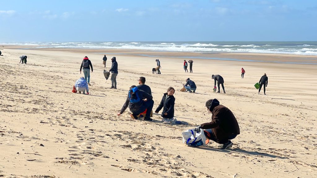 des personnes sur la plage en train de ramasser des déchets