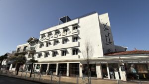 Yatt hotel : un hotel blanc de 3 étage sous le soleil dans une rue commerçante