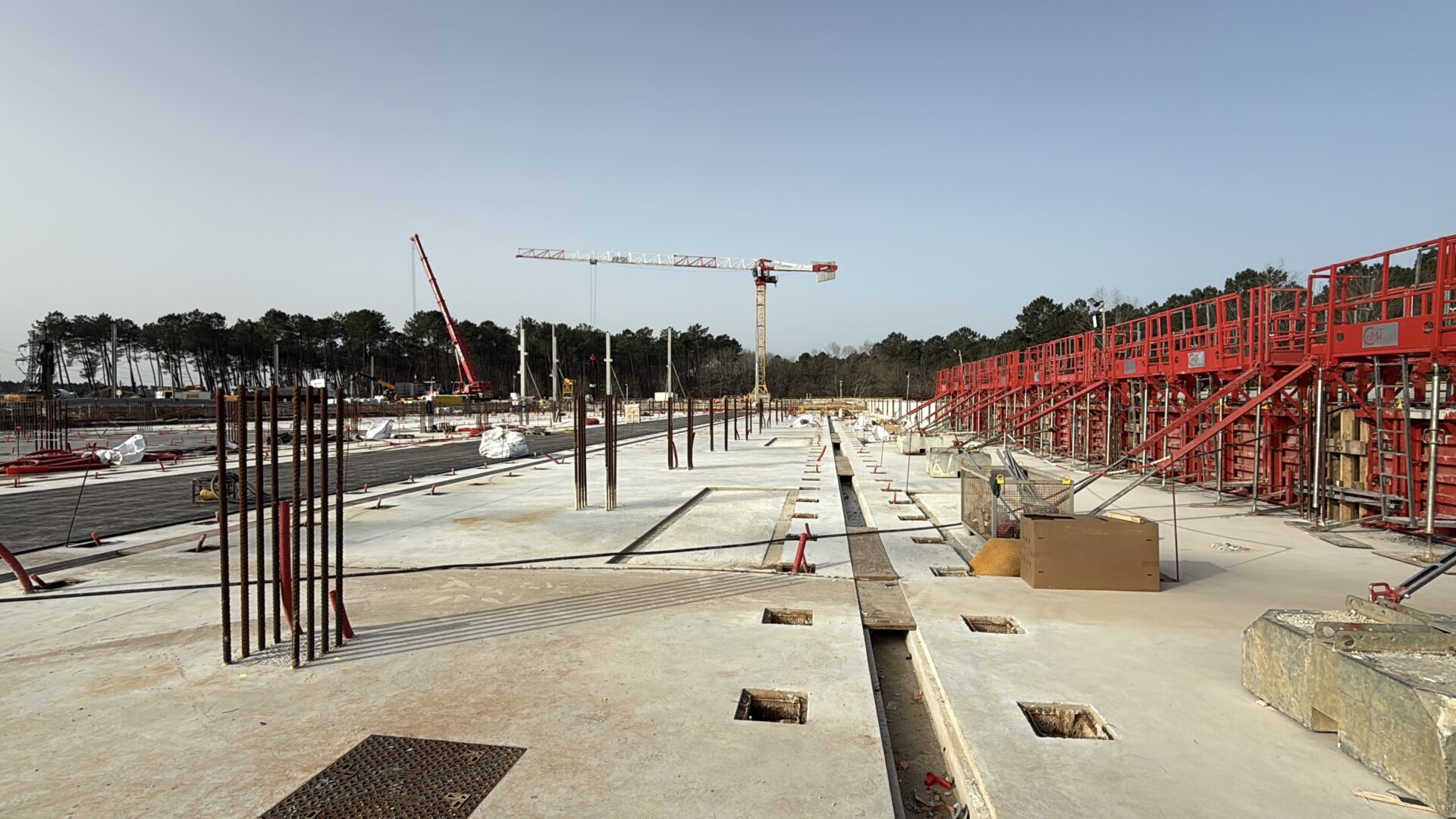 une immense dalle en béton sur un chantier. Au loin une grue