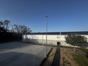 On peut y voir un terrain de tennis en pleins air et un autre terrain de tennis couvert avec sur son toit des panneaux photovoltaïques.