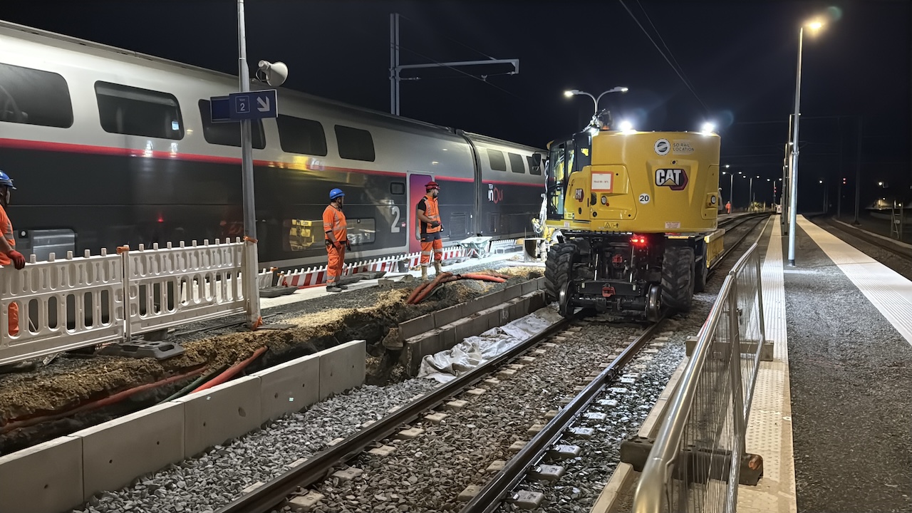 Travaux de nuit sur des voies ferrées. Des hommes travaille sur le chantier en orange