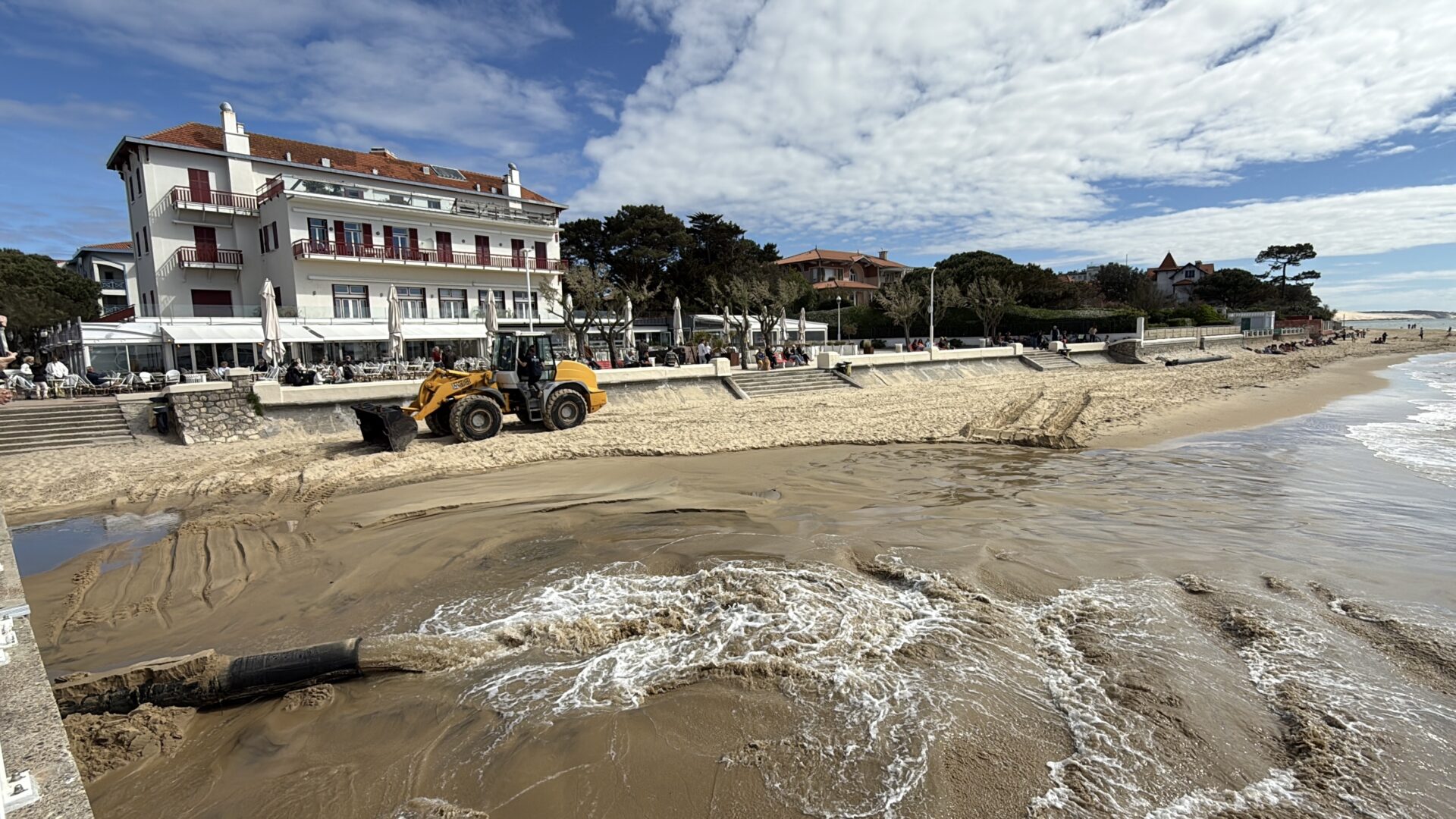 Un tuyausur la plage devant un batiment blanc qui surplombe la mer