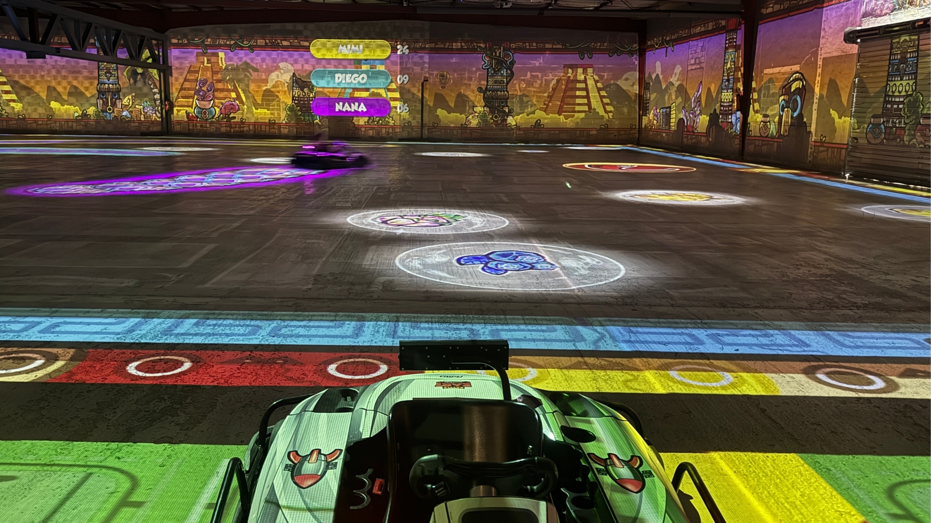 kart au premier plan, piste de karting colorée dans un hangar