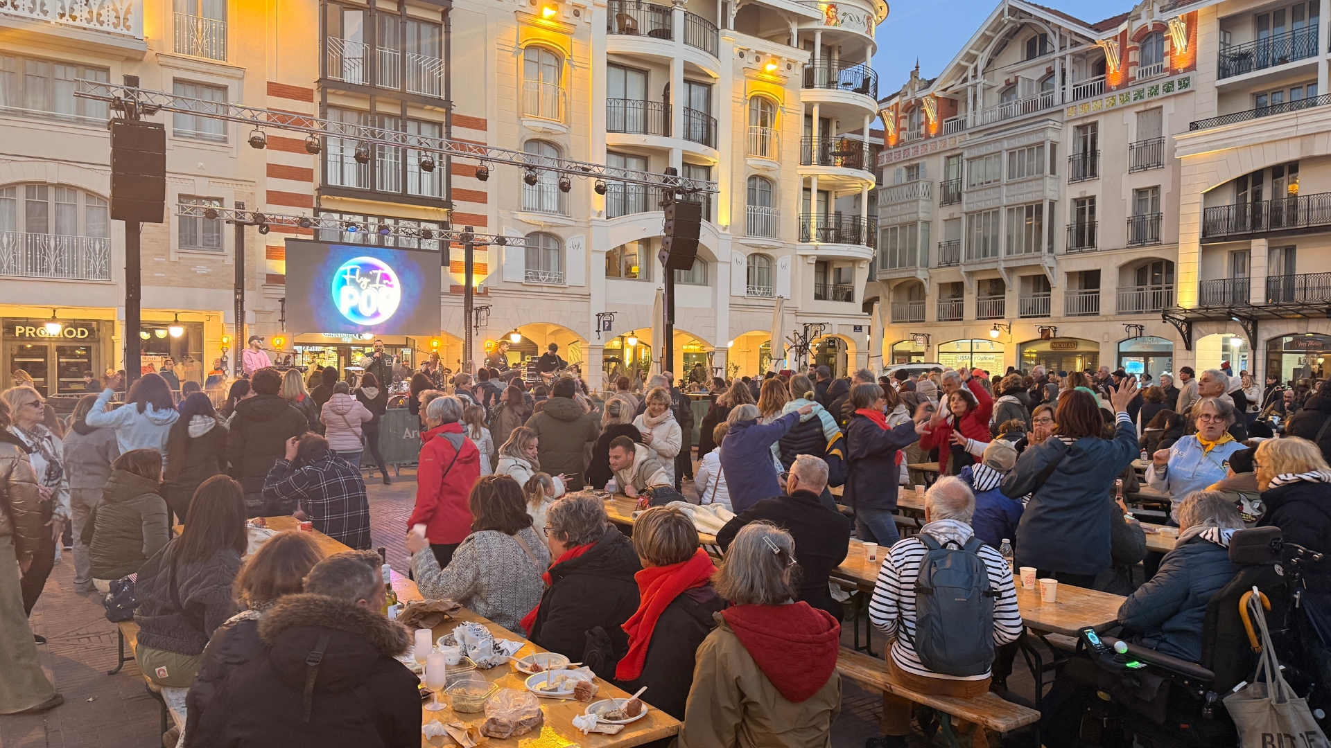 fête d'arcachon : foule de personnes assises à des tables, en arrière plan les immeubles de la place des marquises