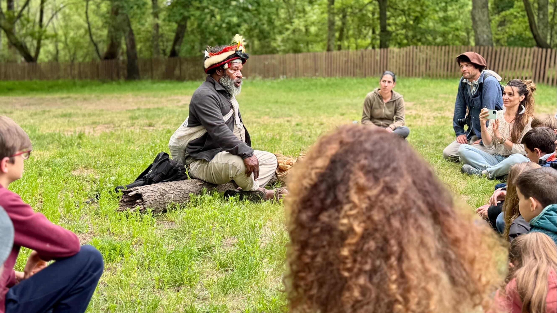 chef papou Mundiya Kepanga assis dans l'herbe avec des personnes autour