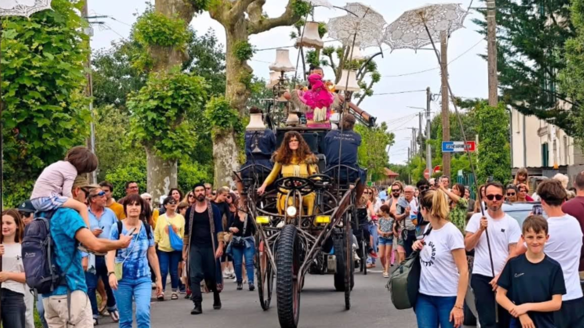 foule de personnes dans une rue d'arès avec au centre un immense véhicule en forme de vélo avec des personnes dessus
