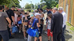 un groupe d'enfant encadré par des adultes dont deux hommes en costard.