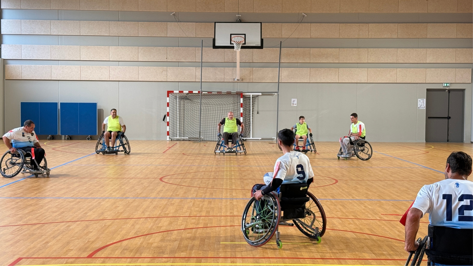 dans un gymnase, des personnes qui pratiquent le rugby sur des fauteuils roulants