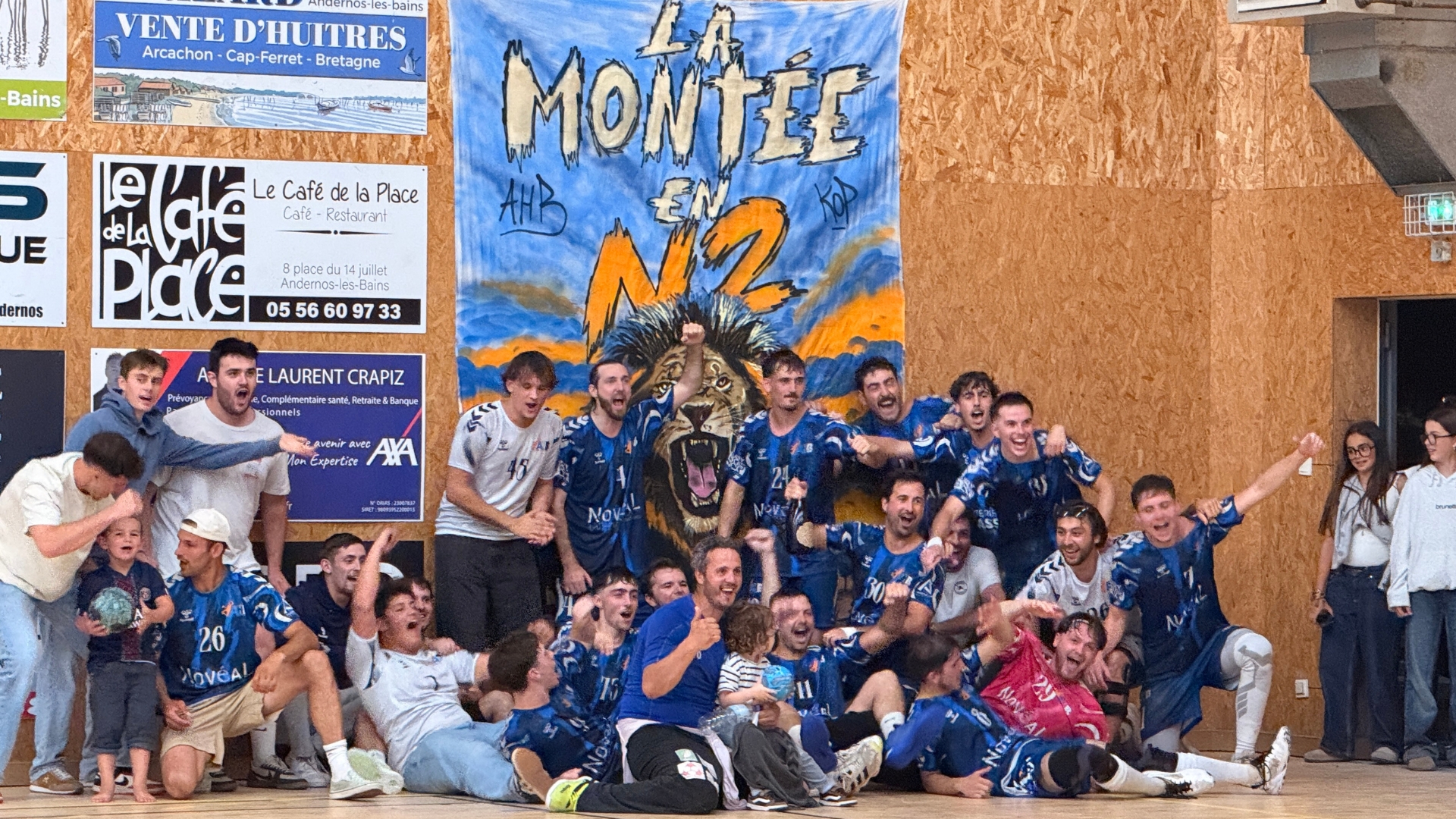 équipe de handball d'andernos devant le mur de la salle de sport avec une inscription "la montée en N2"