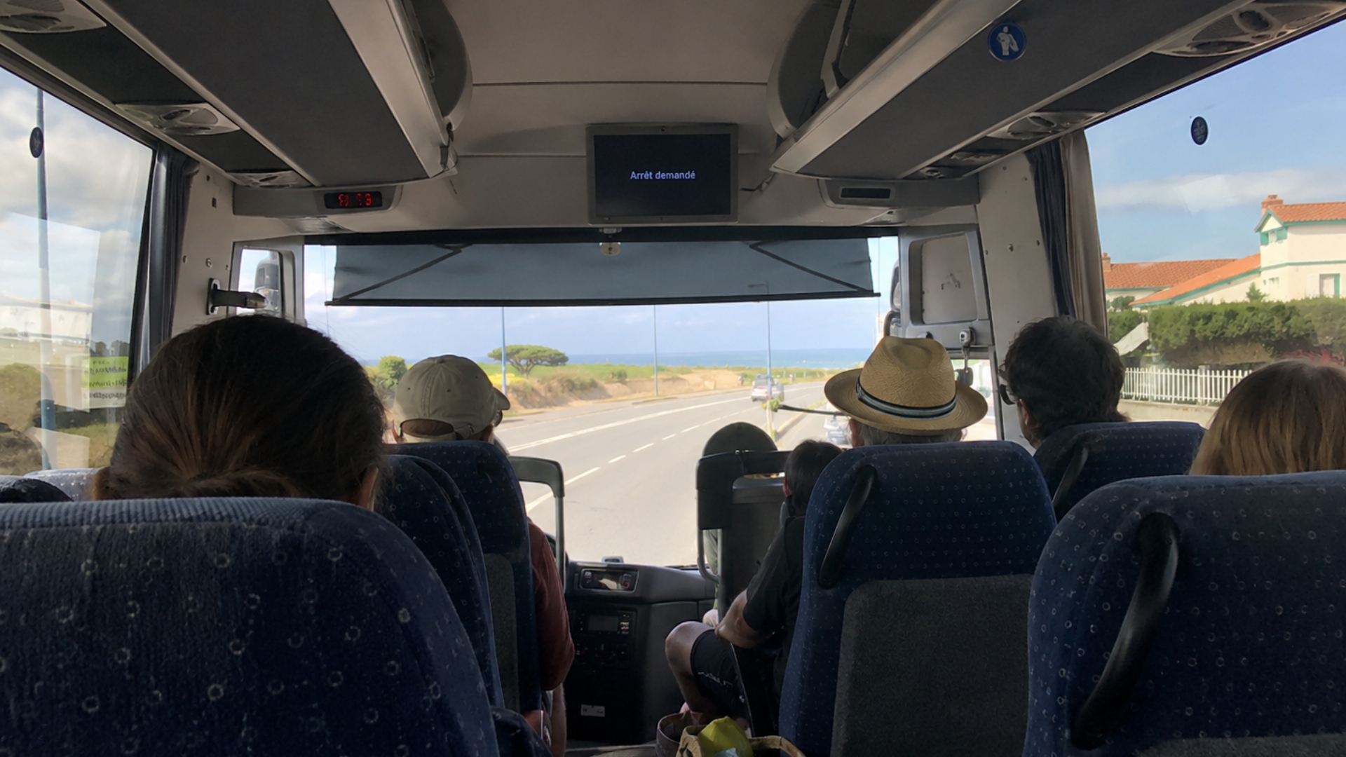 intérieur d'un car régional avec des personnes assises et la plage en arrière plan