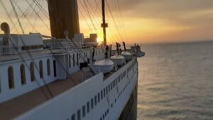 gros plan sur une maquette de Titanic avec la mer et un coucher de soleil en arrière plan