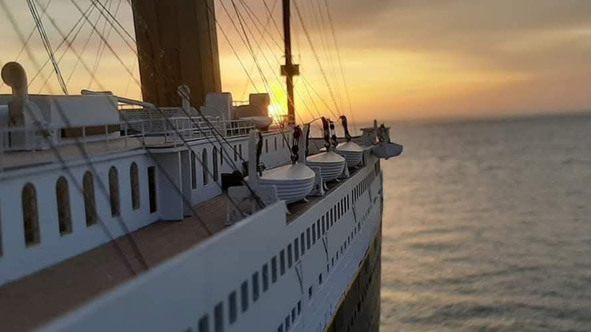 gros plan sur une maquette de Titanic avec la mer et un coucher de soleil en arrière plan