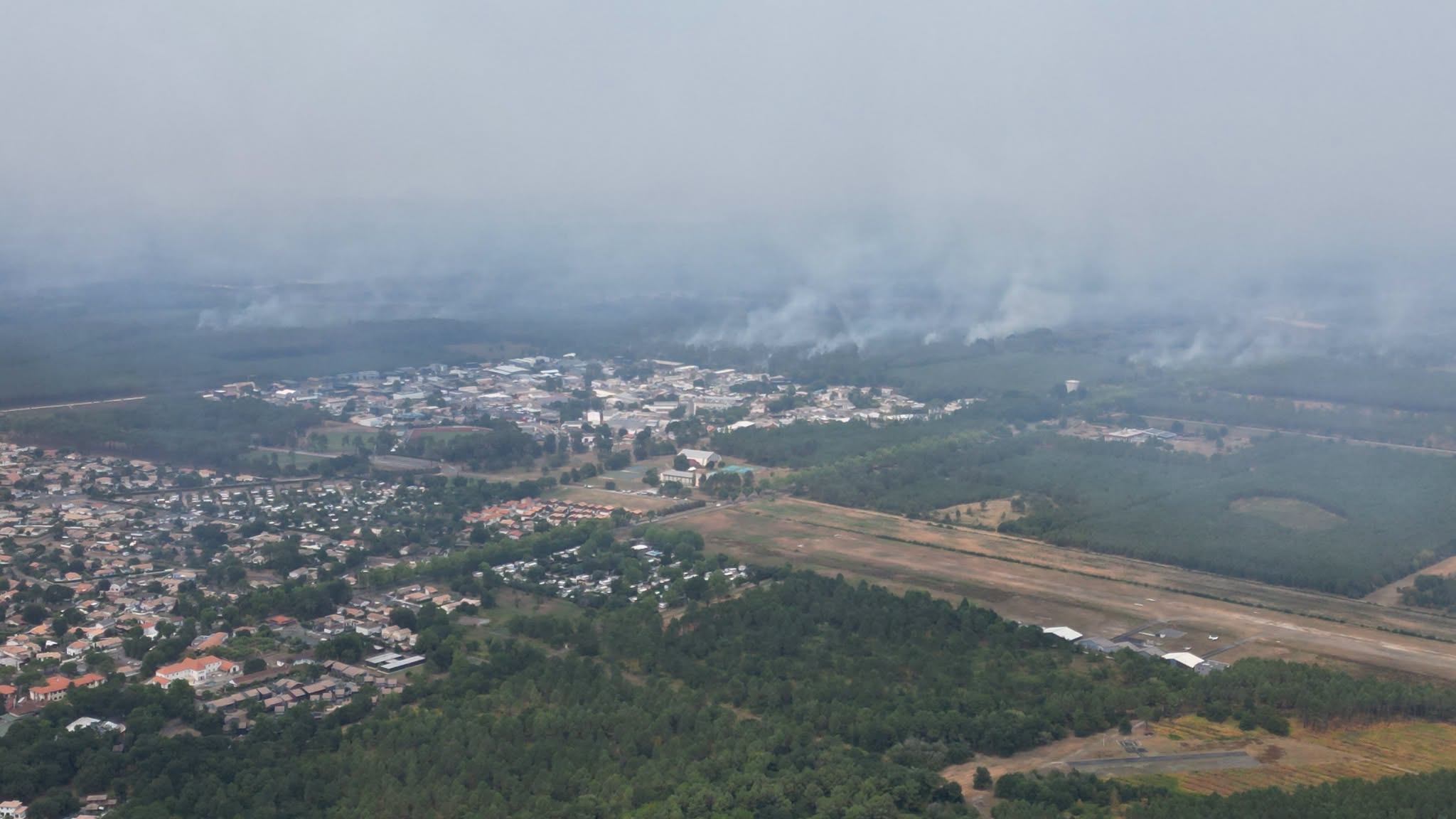 vu du ciel sur une ville et la forêt avec des nuages d'incendie