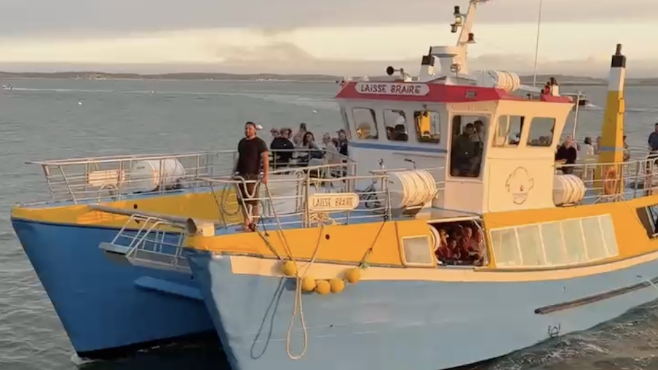 un bateau bleu et jaune transportant des passager sous un soleil matinal