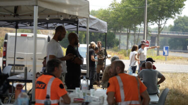groupe de personne sous un barnum deux d'entre elles ont des gilets orange