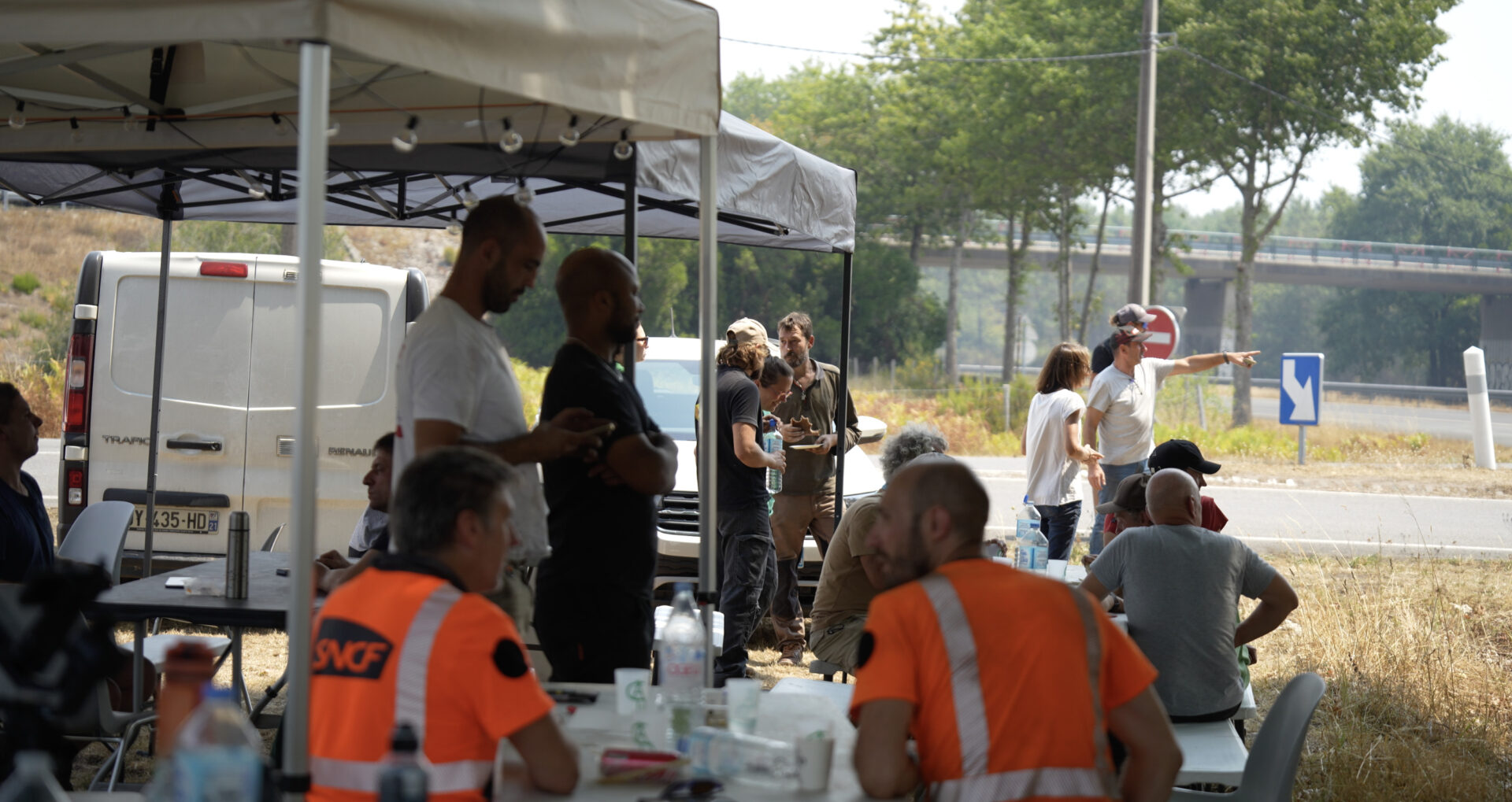 groupe de personne sous un barnum deux d'entre elles ont des gilets orange
