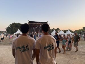 Deux bénévoles font face à la grande scène de Music O Teich. Tous deux portent le tee-shirt du festival, blanc avec un écriture "Music O Teich bleu cyan.