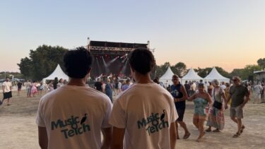Deux bénévoles font face à la grande scène de Music O Teich. Tous deux portent le tee-shirt du festival, blanc avec un écriture "Music O Teich bleu cyan.