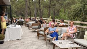 des personnes assises dans des fauteuils sur une terrasse au milieu de la pinède au domaine du ferret