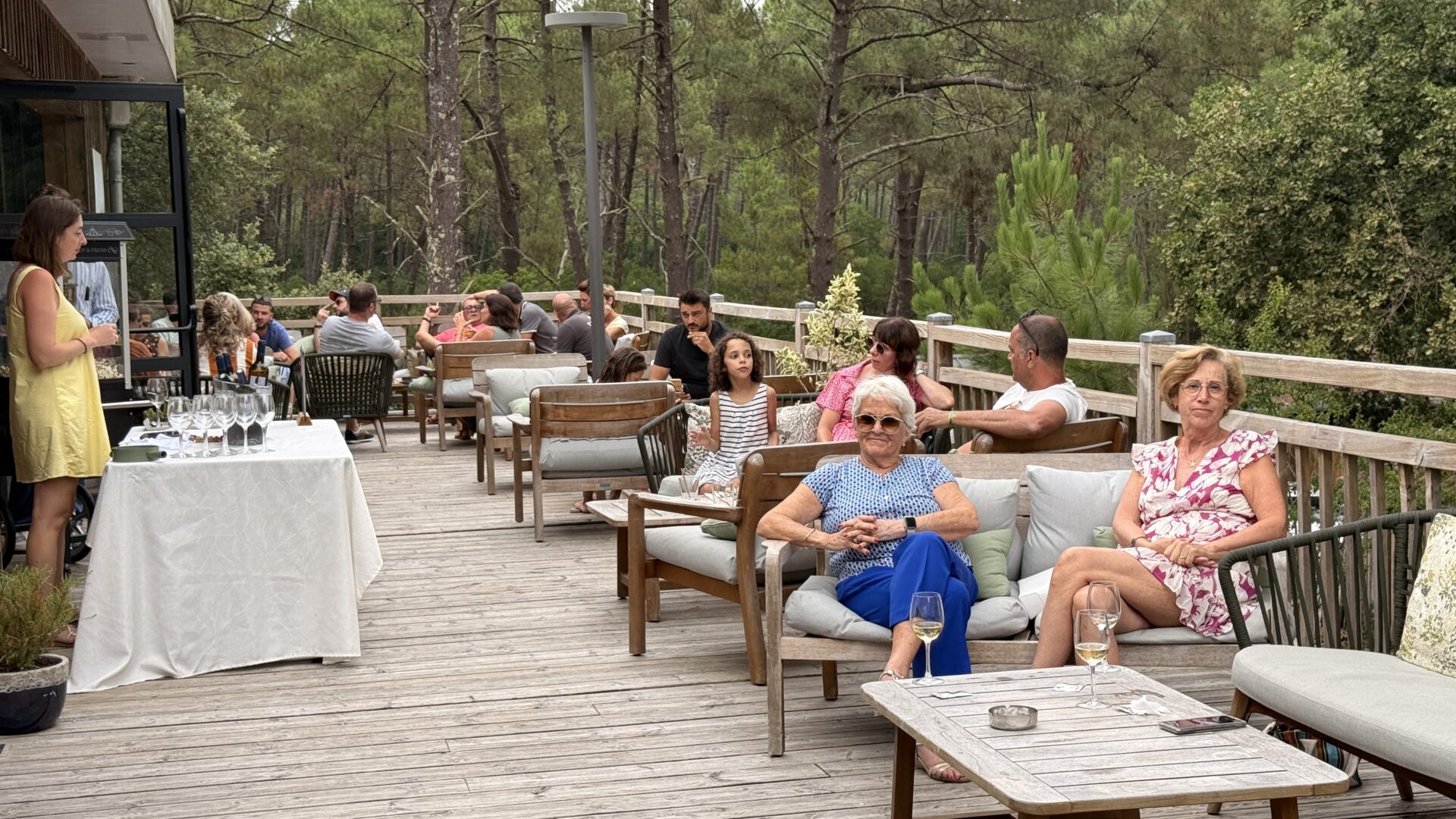 des personnes assises dans des fauteuils sur une terrasse au milieu de la pinède au domaine du ferret
