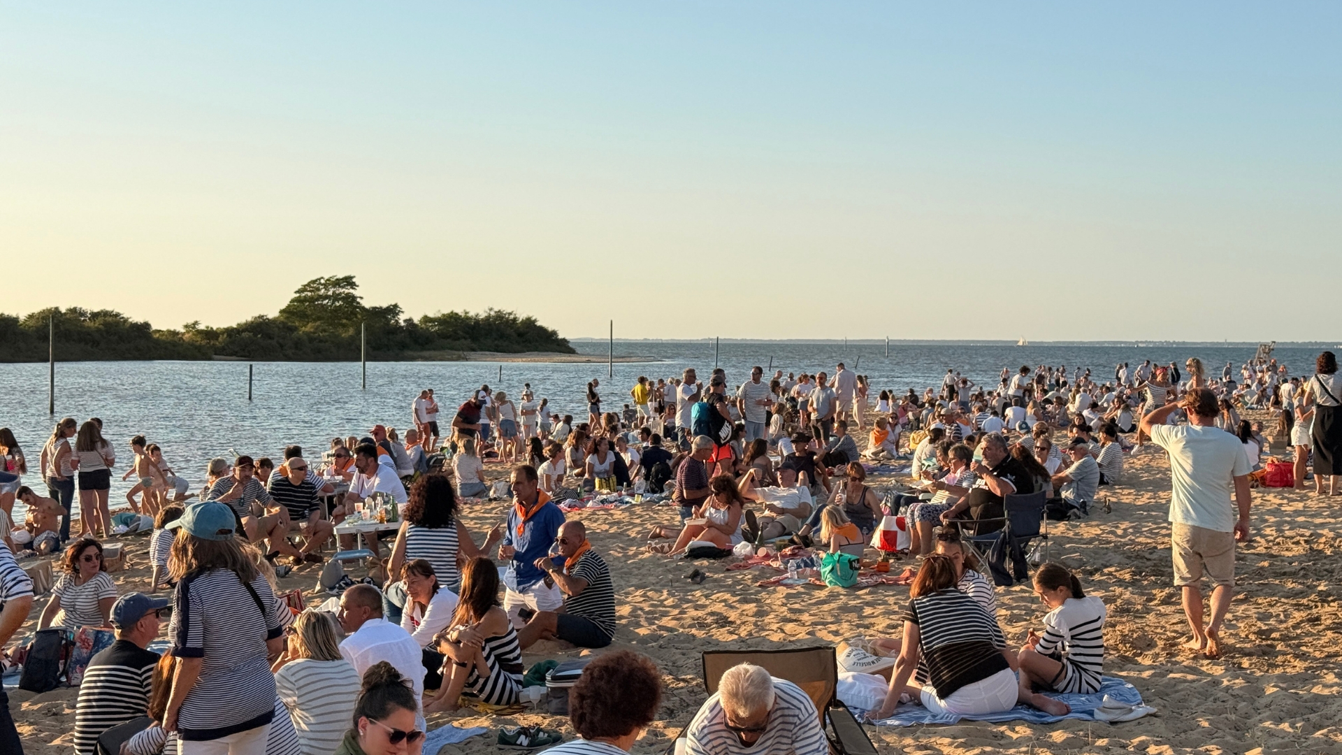 beaucoup de personnes assises dans le sable sur la plage de la hume pour la soirée barrée