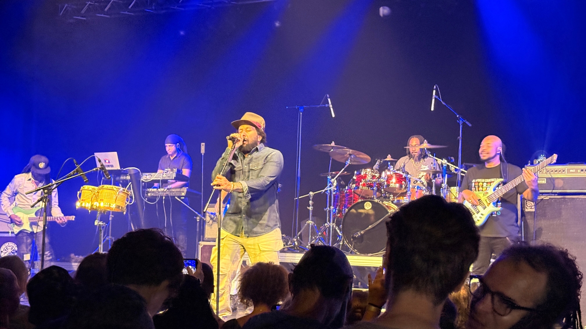 ky-mani marley sur la scène du théâtre cravey avec des musiciens autour pour l'african vibes festival
