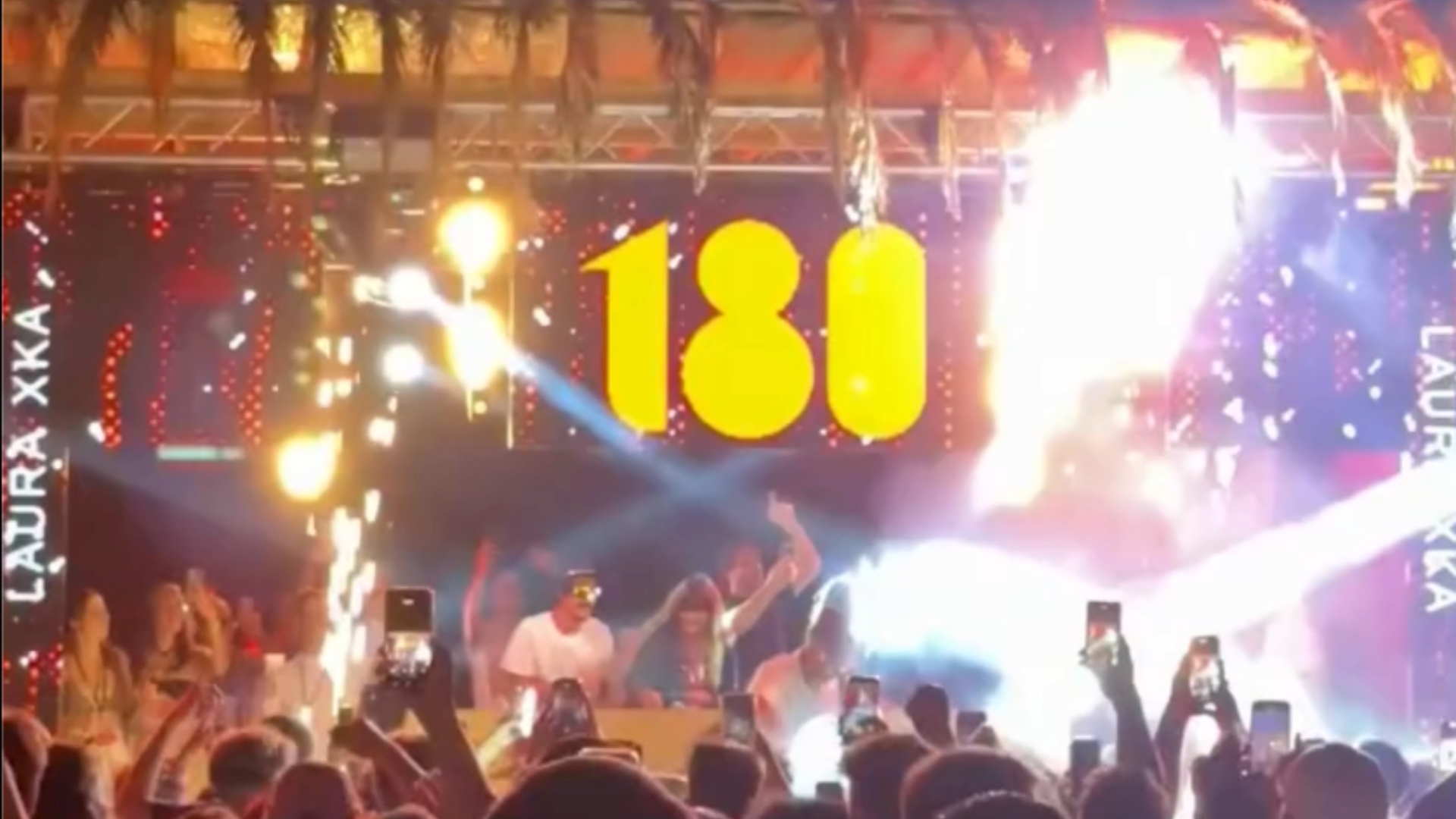 concert : des personnes en fosse devant une scène avec néon 180