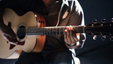 Un homme assis qui joue de la guitare acoustique