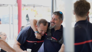 deux pompiers qui rient en se prenant dans les bras