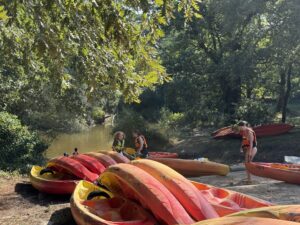 Plusieurs canoë rouge et jaune sont sur une plage près de la Leyre