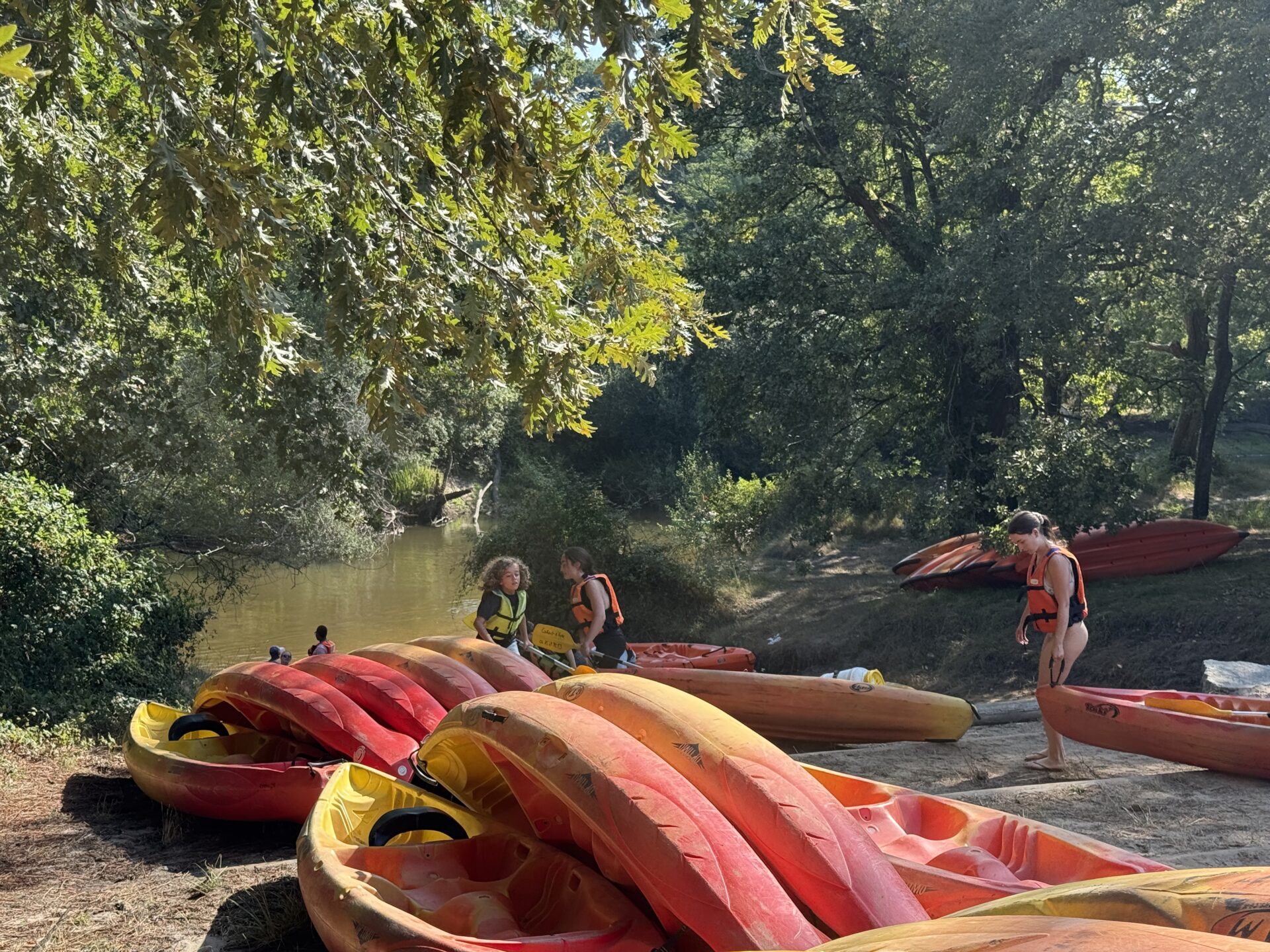 Plusieurs canoë rouge et jaune sont sur une plage près de la Leyre