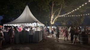 Le marché gourmand d'Arès de nuit. On peut voir, une tente et une foule devant celle-ci.