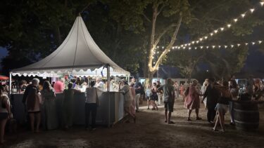 Le marché gourmand d'Arès de nuit. On peut voir, une tente et une foule devant celle-ci.