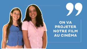 Deux jeunes femmes se tiennent côte-à-côte sur le bord gauche de l'image et sourient. A droite, sur un fond bleu azur, une écriture blanche surplombée par des guillemets anglais explique "On va projeter notre film au cinéma".
