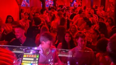 un groupe de jeunes personnes dans un cliub éclairé de rouge