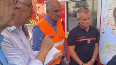 Un groupe d'homme devant une carte dont un pompier et un homme portant un gilet orange