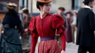 Une femme en robe rouge dans la rue, reconstitution d'autrefois