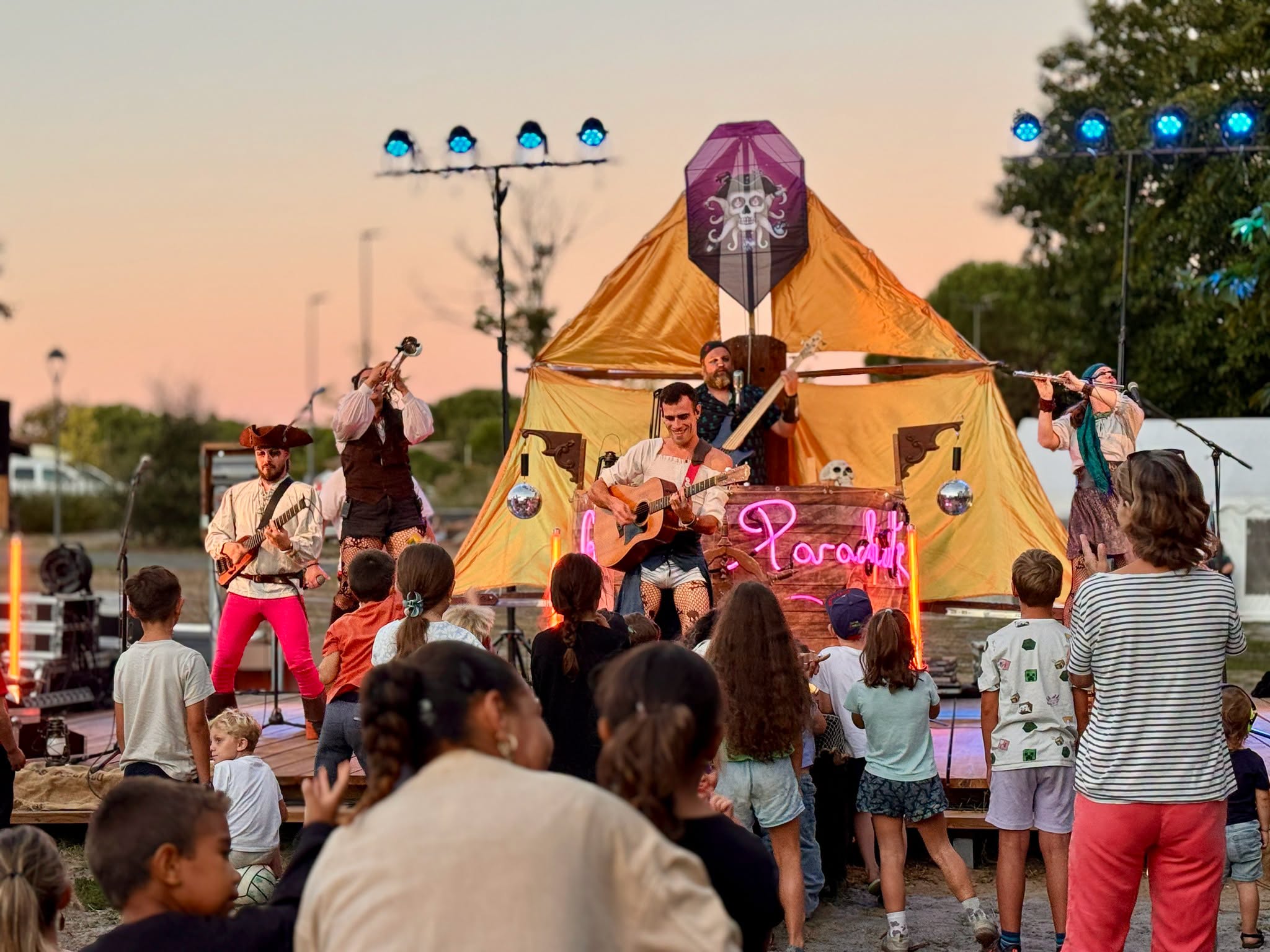 une troupe de cirque devant le public, coucher de soleil dans le fond