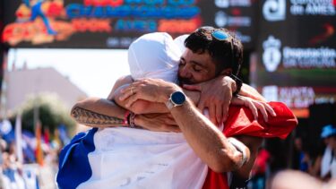 Deux hommes entourés d'un drapeau tricolore se prennent dans les bras à l'arrivée d'une course