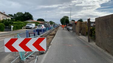 une rue avec des barrières de chantiers et un panneaux avec des fleches rouges et blanches vers la gauche
