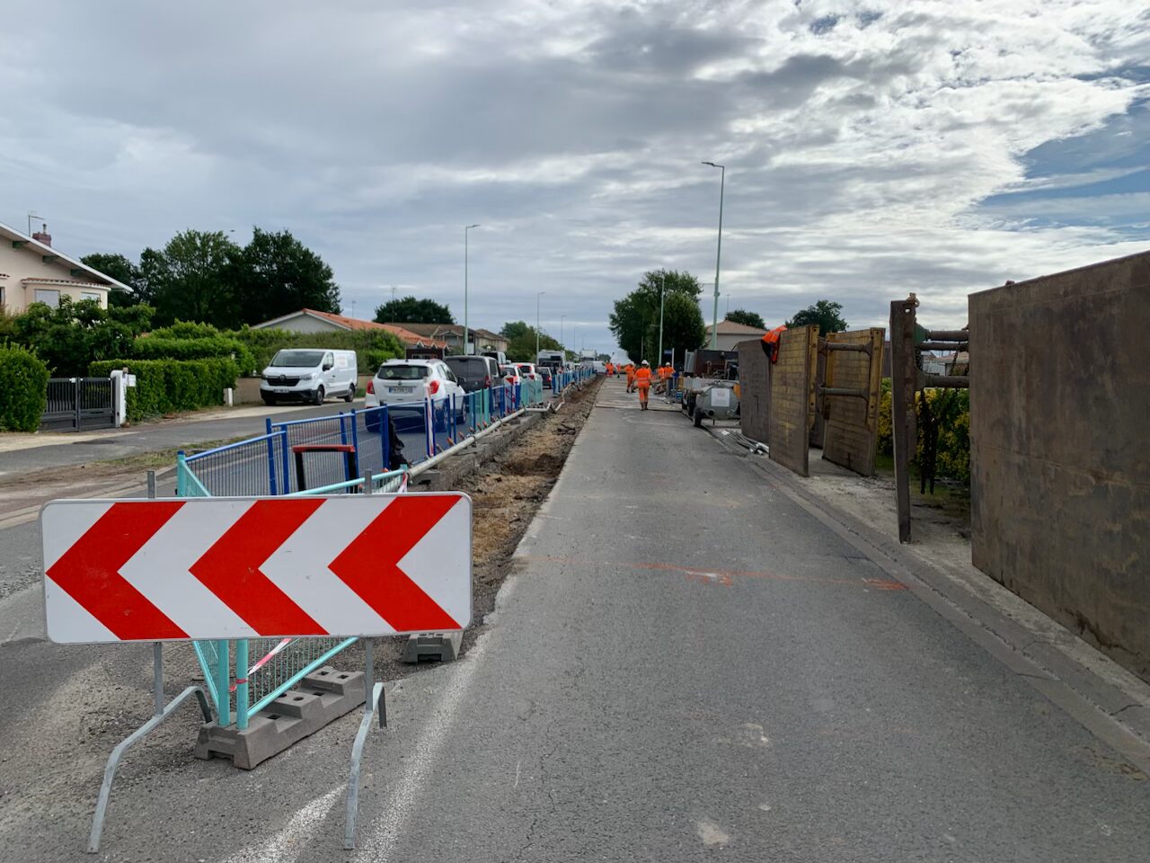 une rue avec des barrières de chantiers et un panneaux avec des fleches rouges et blanches vers la gauche