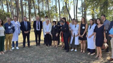 Des hommes et des femmes posent en ligne devant des pins , certains d'entre eux ont de sblouses blanches d emédecins