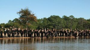 Des hommes et des femmes en noir sur les rives d'un bassin d'eau