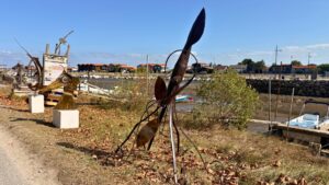 sculpture en acier représentant un animal marin dans l'herbe avec le port de La Teste en arrière-plan pour le festival Alias