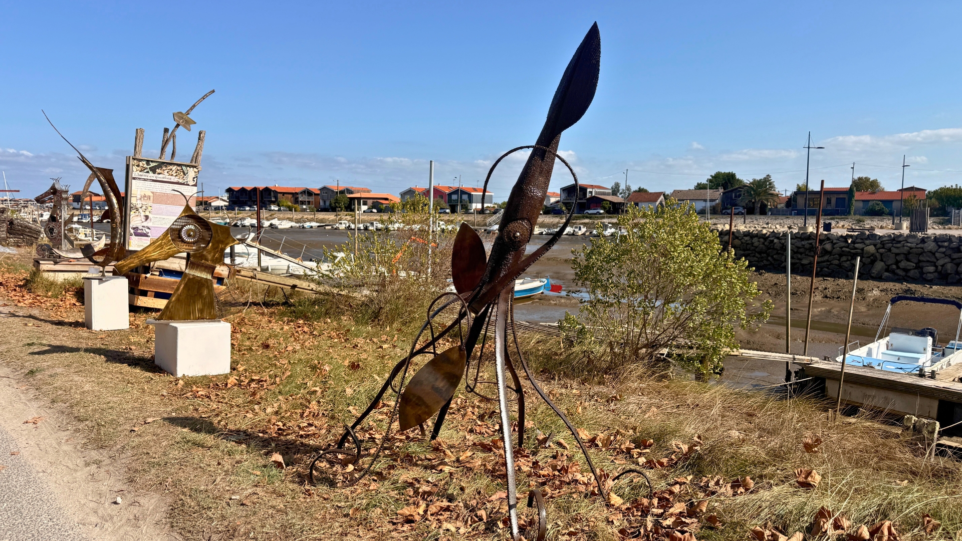 sculpture en acier représentant un animal marin dans l'herbe avec le port de La Teste en arrière-plan pour le festival Alias