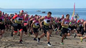 des sportifs en combi de plongée en train de courir sur la plage lors du swimrun du bassin d'arcachon