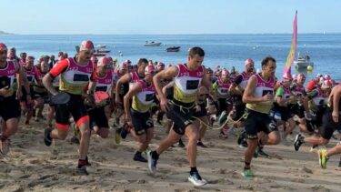des sportifs en combi de plongée en train de courir sur la plage lors du swimrun du bassin d'arcachon